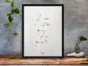 framed-art-print-standing-on-a-wooden-desk-against-a-concrete-wall-near-a-hand-decoration-a10403.webp